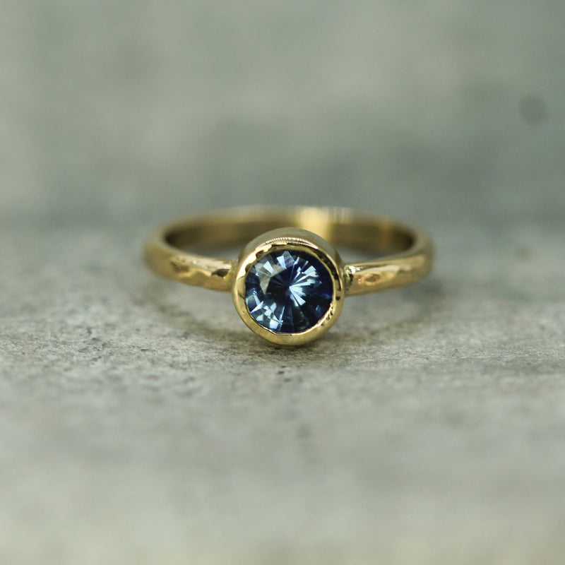 Gold ring with a blue sapphire on a textured surface