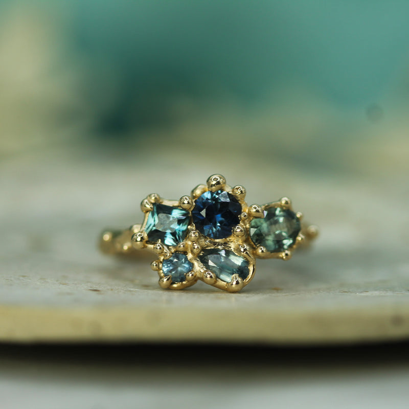 Gold ring with blue sapphires  on a blurred natural background