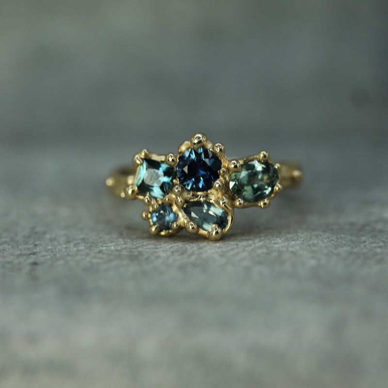 Gold ring with blue sapphires 
on a gray background