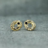 Gold earrings with dark blue sapphire gemstones on a gray surface