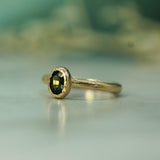 Gold ring with a green sapphire on a blurred background