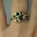 Blue and green sapphires set in 14k yellow gold ring on hand 