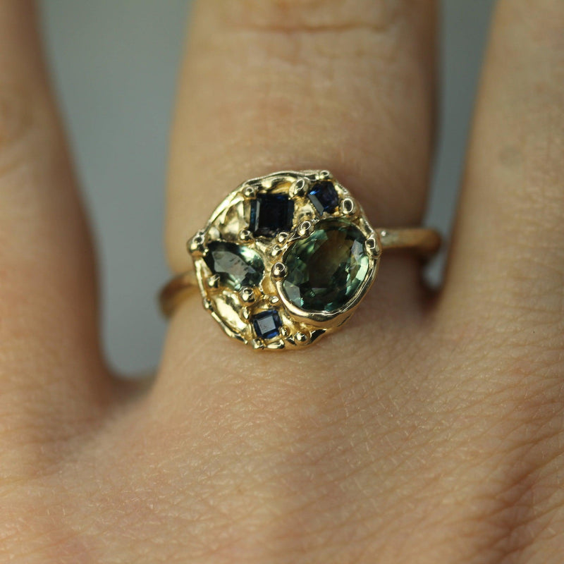 Blue and green sapphires set in 14k yellow gold ring on hand 