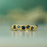 Gold ring with embedded blue sapphires on a blurred green background