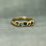 Gold ring with embedded blue sapphires on a textured surface