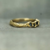 Gold ring with embedded blue sapphires on a textured surface