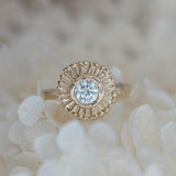 Handcarved sun beams surround a diamond in yellow gold 