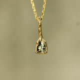 melty ocean inspired small gold pendant with a teal sapphire 